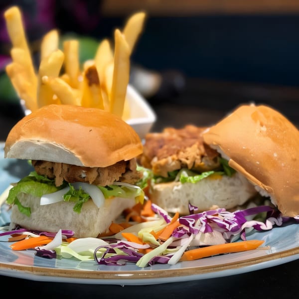 Two Indian-style sliders with lettuce, onions, and shredded meat, served with fries and coleslaw.