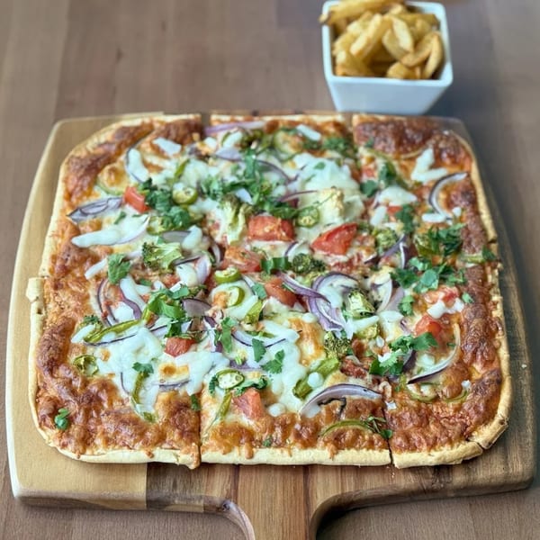 Amrut's Indian-style pizza with vegetables and cheese, served with a side of fries.